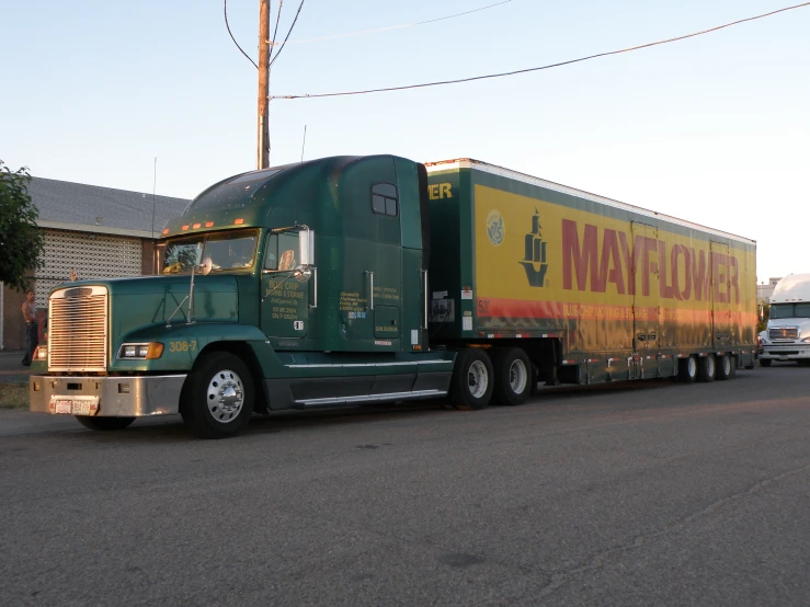 a green and yellow semi truck with a green trailer behind it