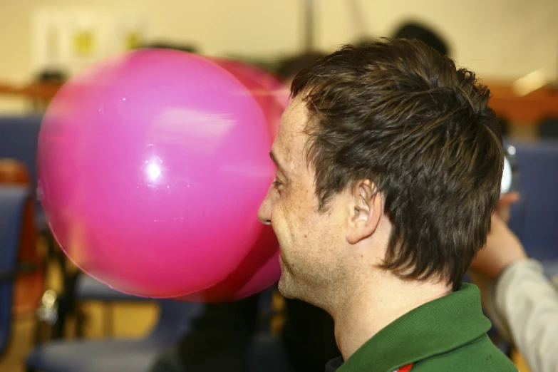 man in green shirt holding pink balloon near him