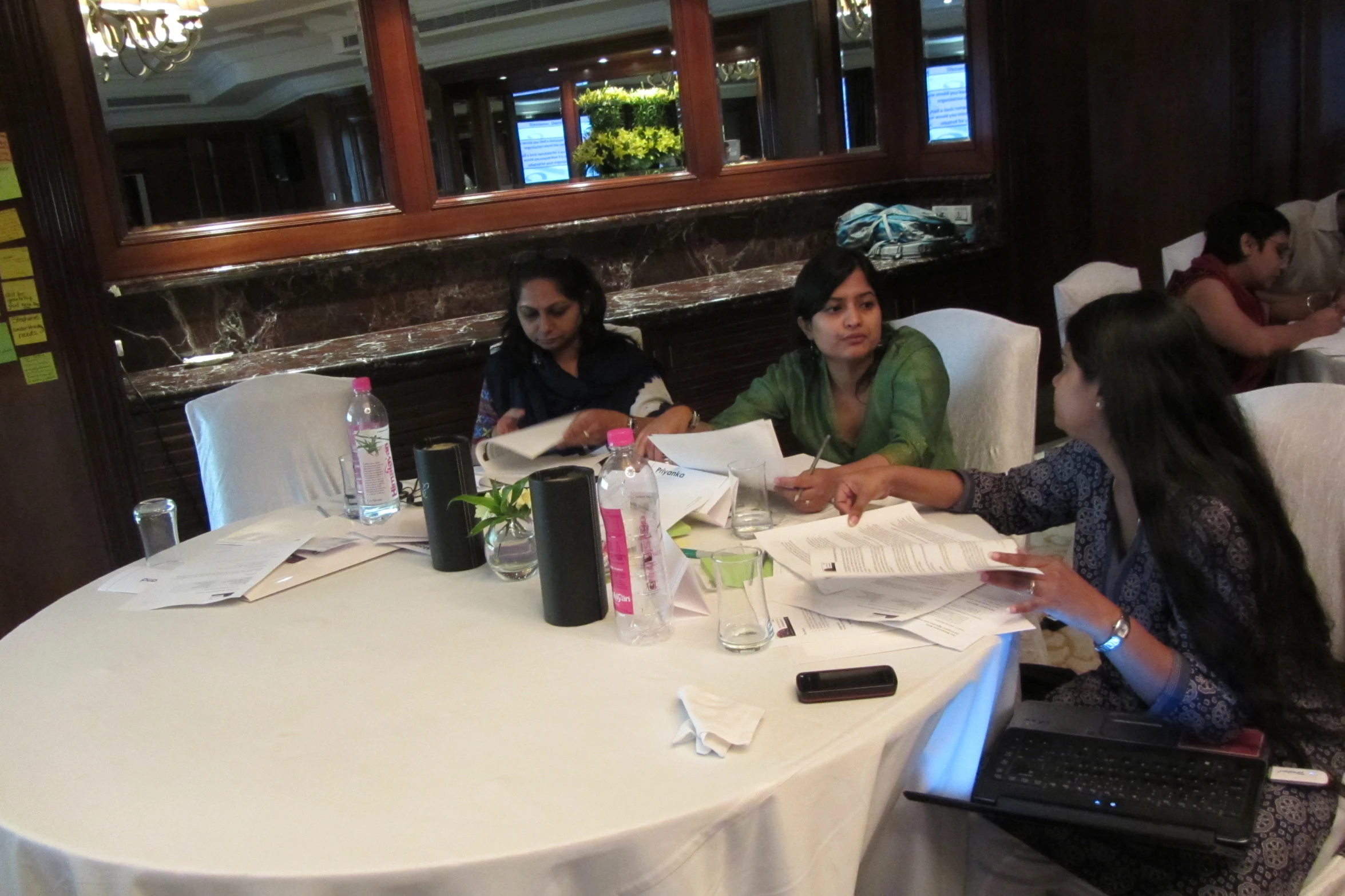 a group of people sitting at a round table in front of laptops