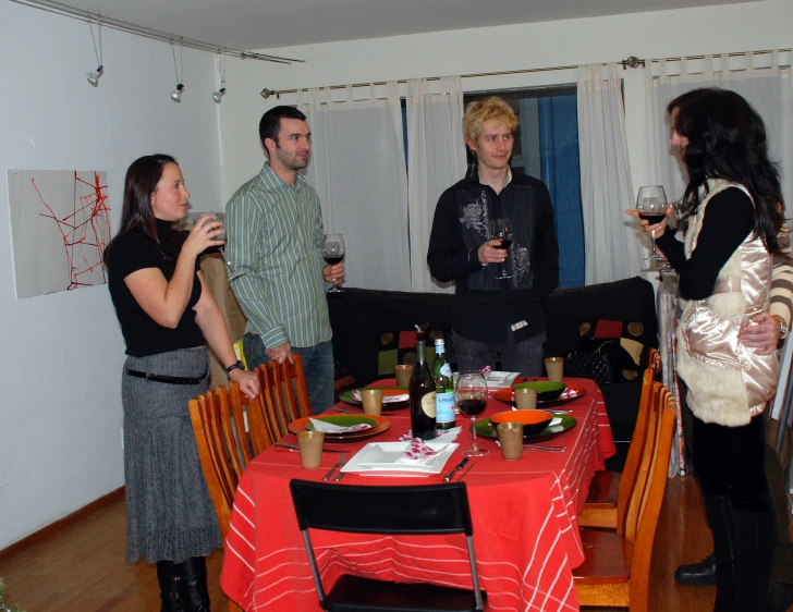 people are gathered around a table drinking wine