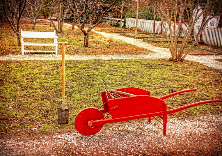 a red wagon on the ground next to a small bench