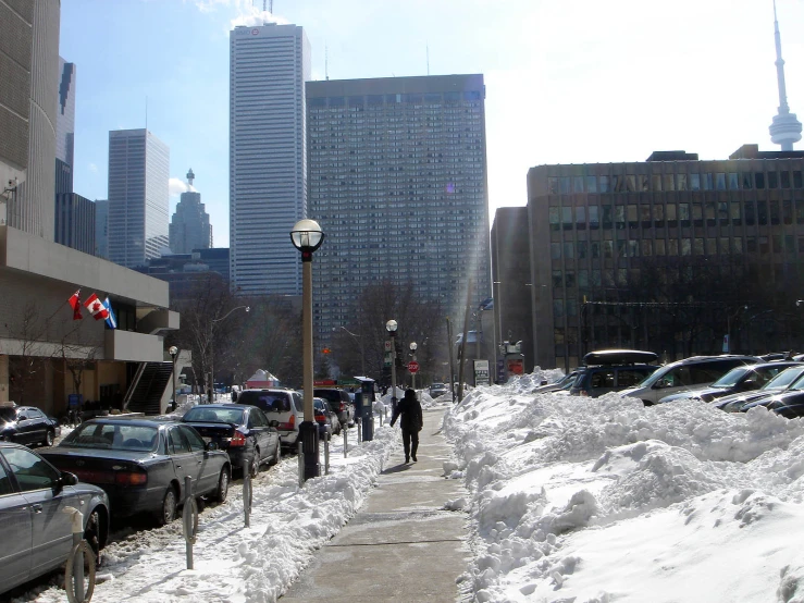 many people are walking in the snow on a city sidewalk