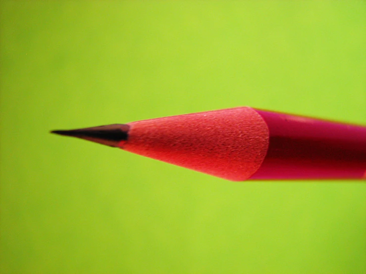 a red pencil leaning up against a green background