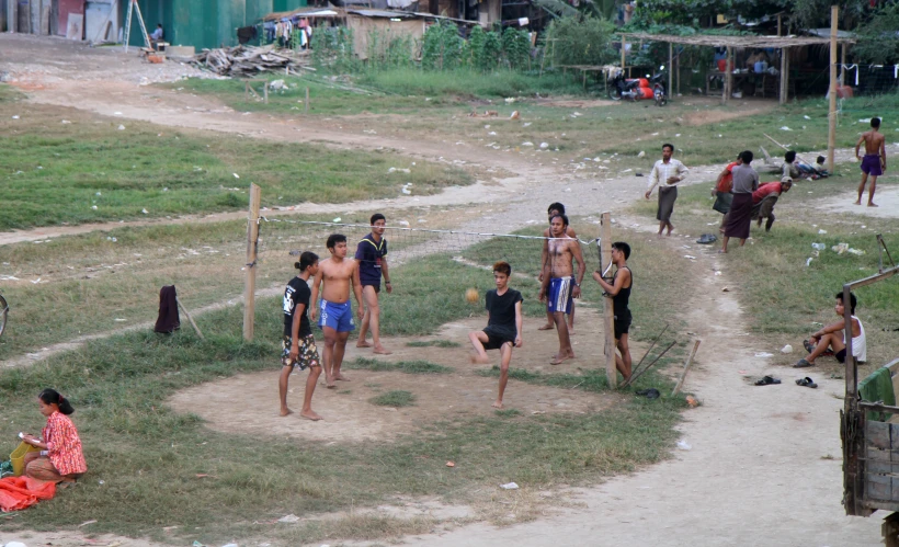 several children playing soccer in the dirt