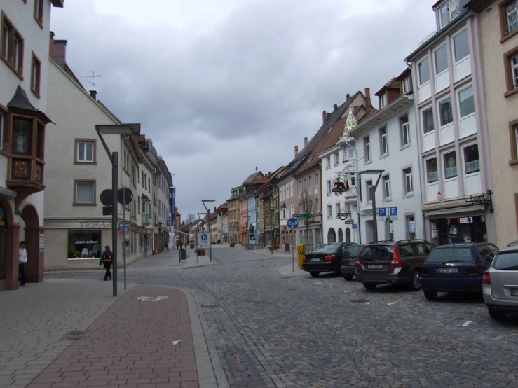 a narrow street with cars parked at the curb