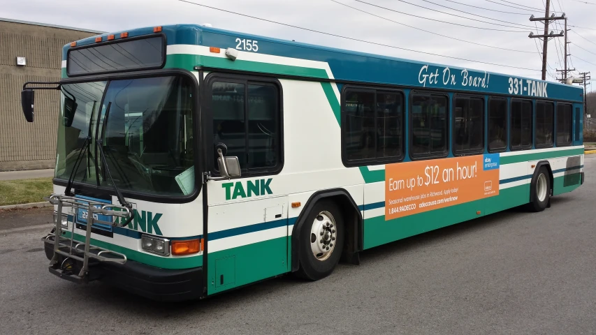 a blue, white and green bus is stopped in a parking lot