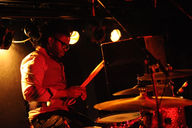 man in sunglasses playing drums on stage at night