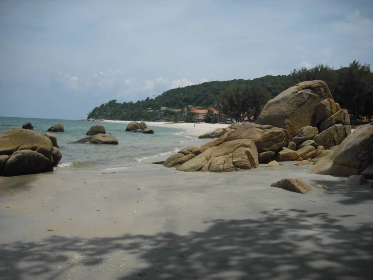 the sun is shining on an sandy beach with rocks and water