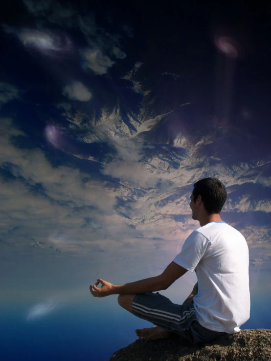 a man sits on a rock and meditates in the foreground, with clouds in the sky