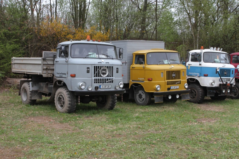 three trucks parked next to each other on a grass covered field