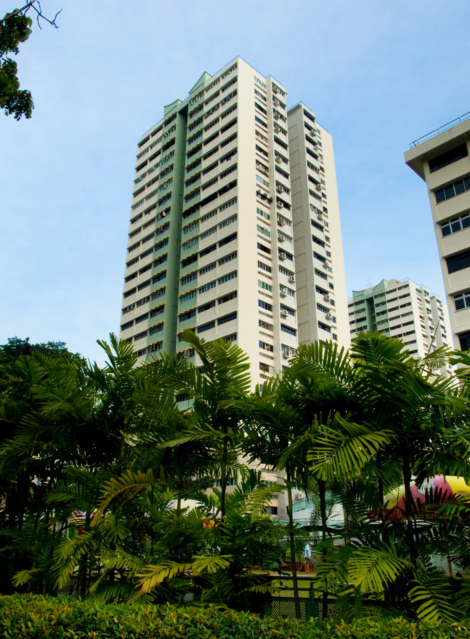 two tall buildings sitting next to trees and bushes