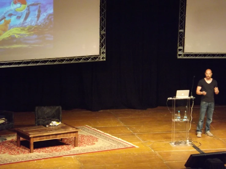 a man is standing behind a podium with an electronic projector in front of him