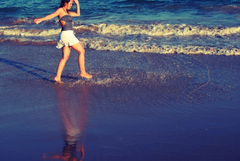a woman in shorts walks on the beach by water
