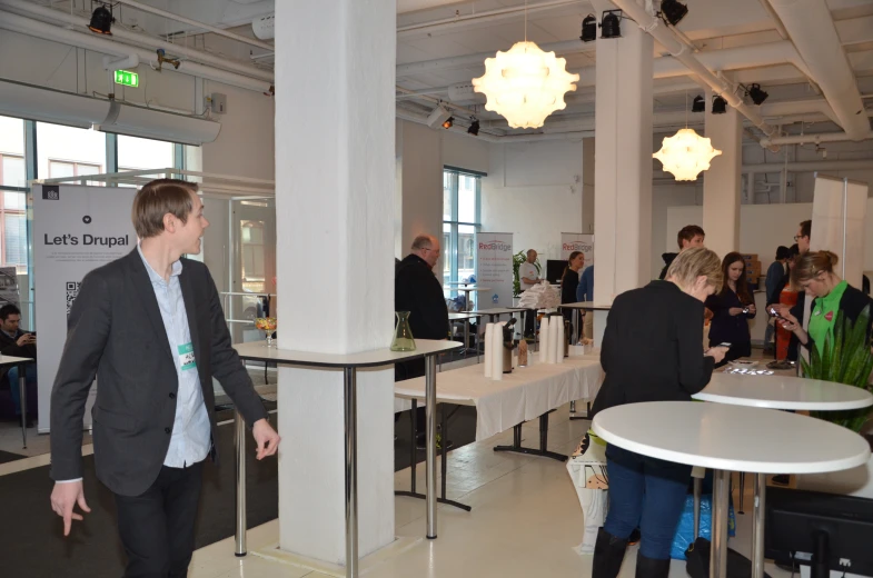 group of people walking around a building filled with lots of white tables