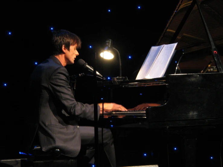 a man playing a piano in front of a microphone