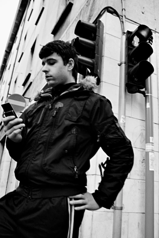 a man standing next to a traffic light while looking at his cell phone