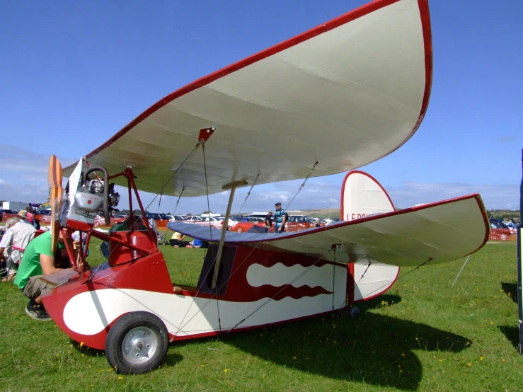 a plane is parked on some grass with people standing around it