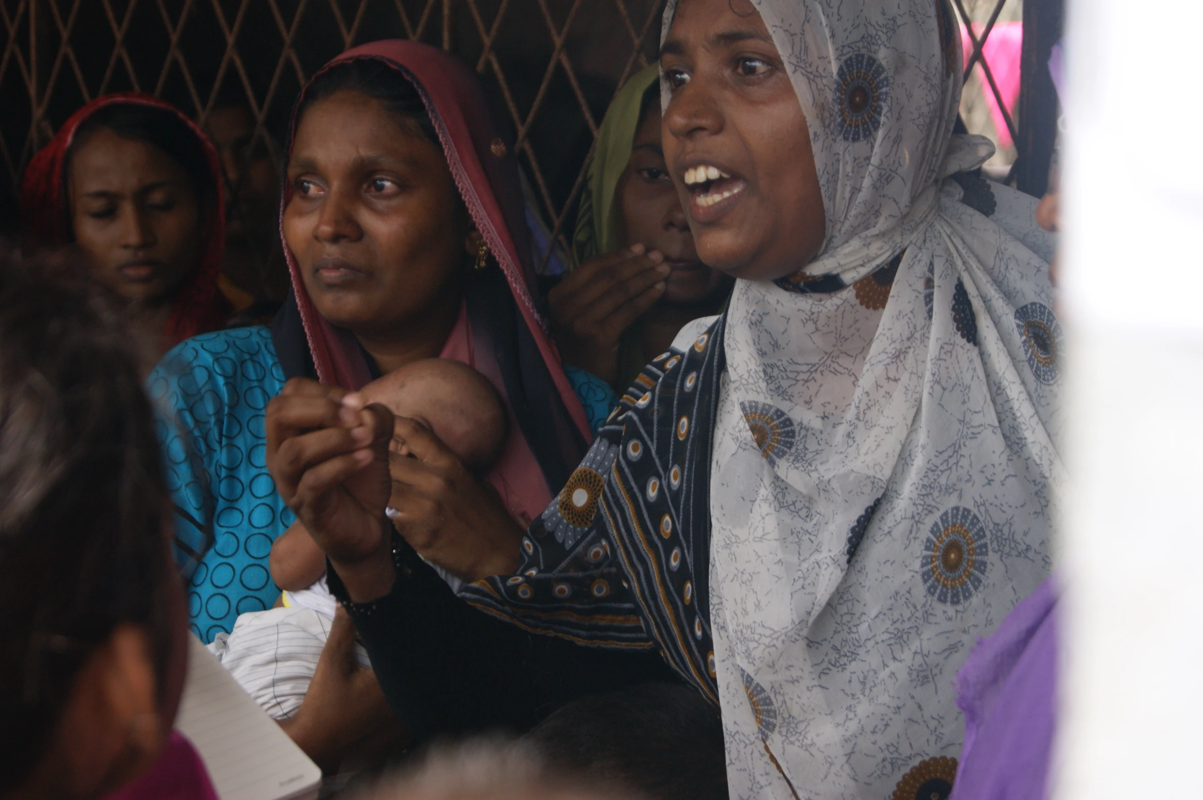 a group of women wearing headscarves standing and laughing