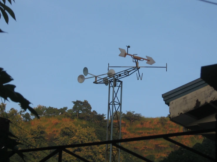 several antennas on top of a pole next to trees