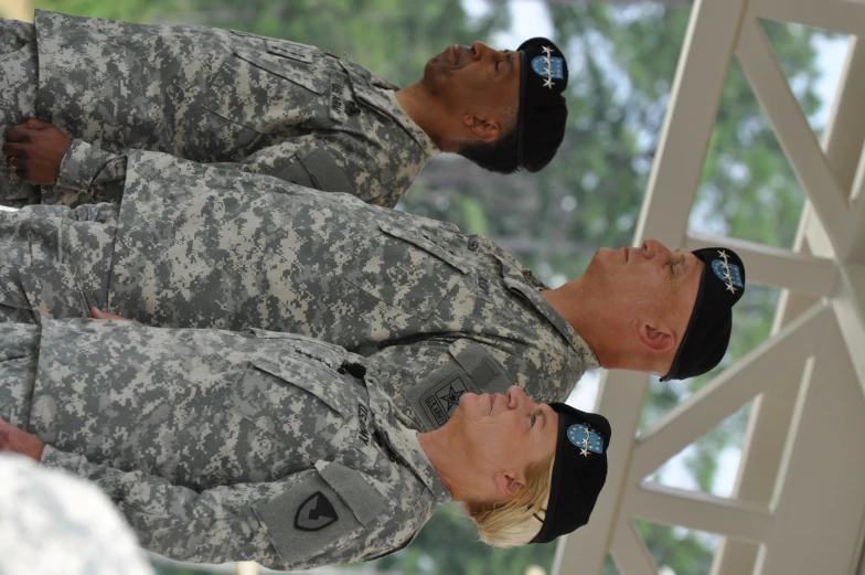 two military men in camouflage standing with their arms together