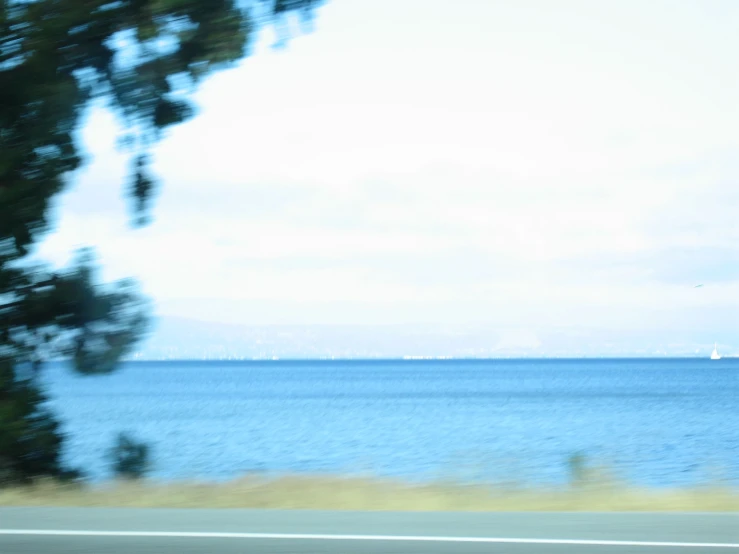 view from vehicle to the ocean with ships passing by