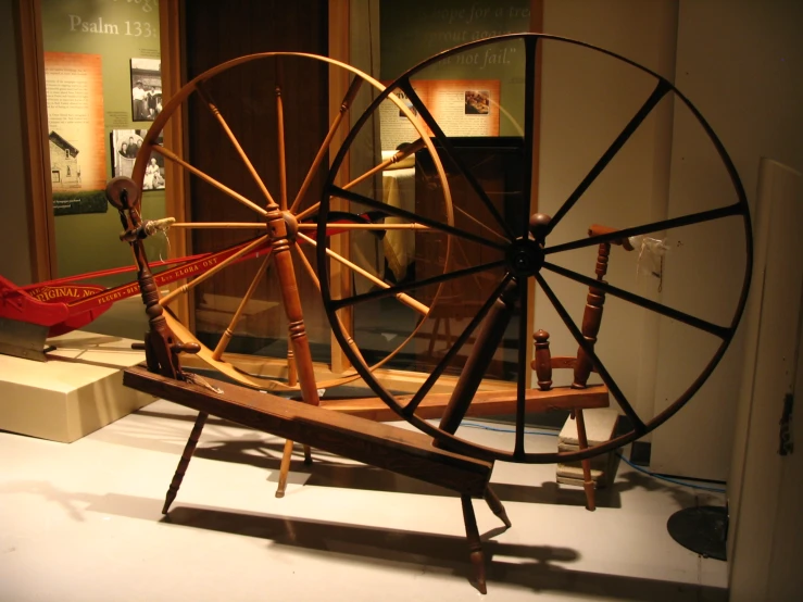 wooden spinning wheel sitting in an exhibit setting