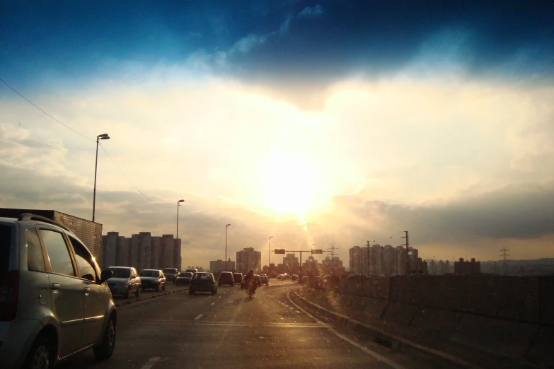 the sun rising over a city while cars are traveling on the road