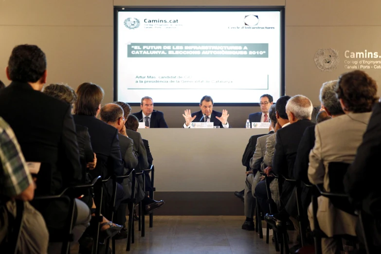 a group of people sit in front of a large screen