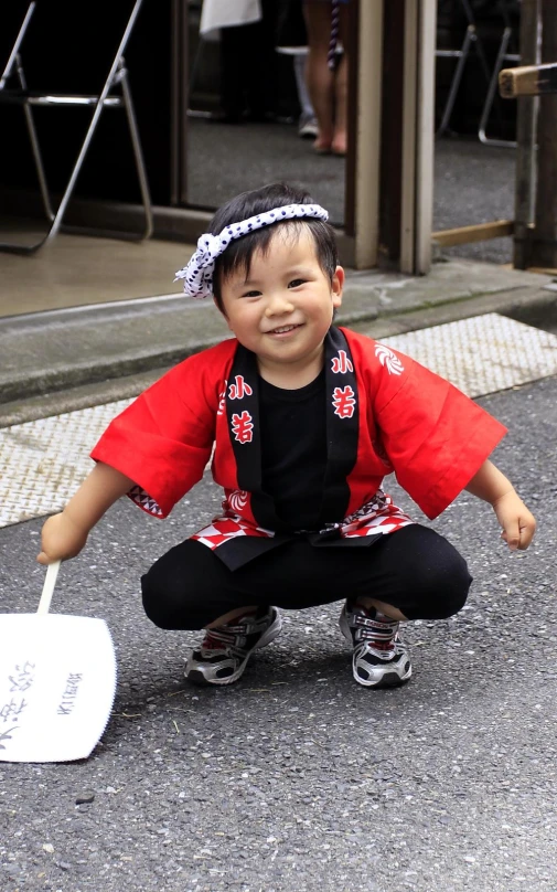 the smiling child is wearing an asian dress