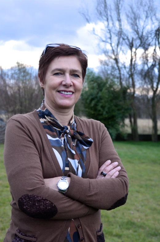 a woman in a brown sweater is smiling for the camera