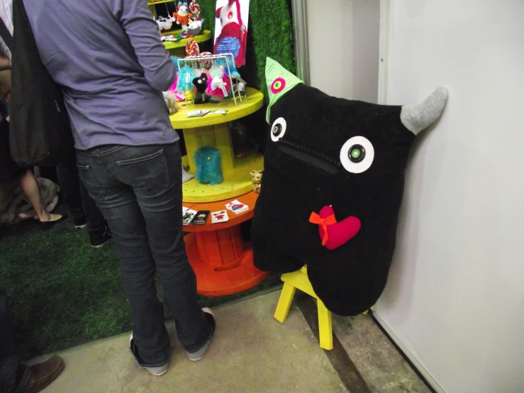 a black monster pillow and toy next to a table with other toys