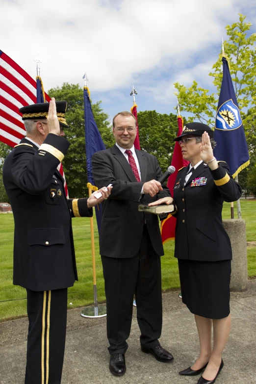 three people in suits and uniforms hold their hands high