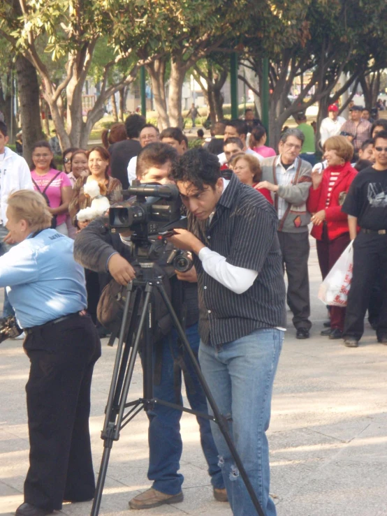 a man looking through a video camera at a crowd of people