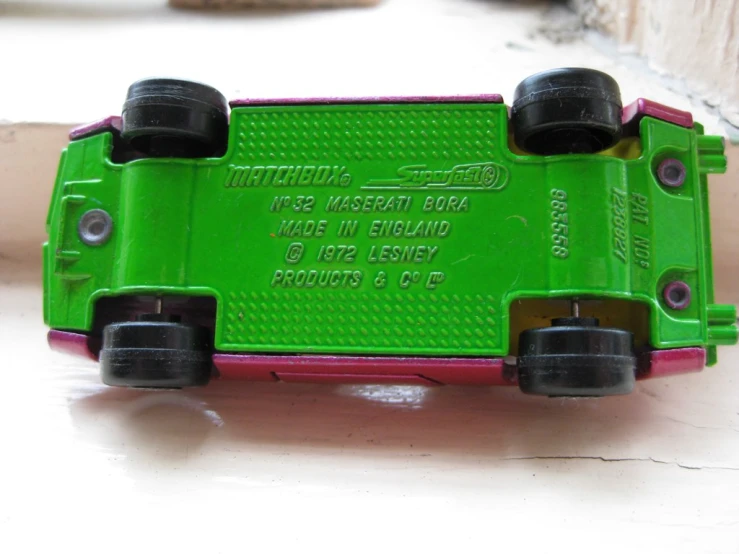 a green toy car sitting on top of a white table