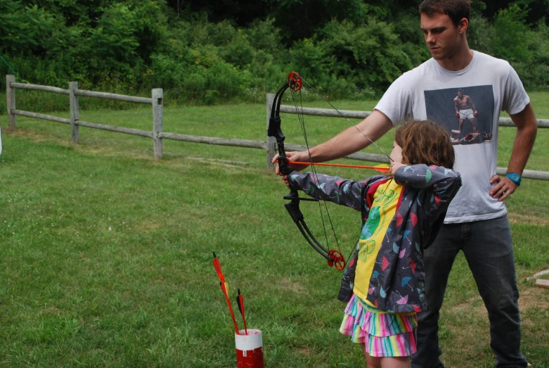 a father teaching his daughter how to practice archery