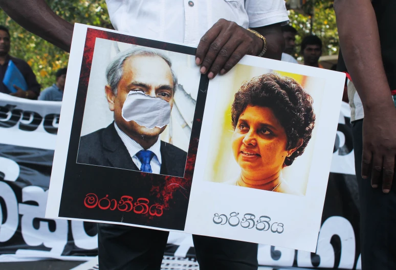 two people holding posters in front of a crowd