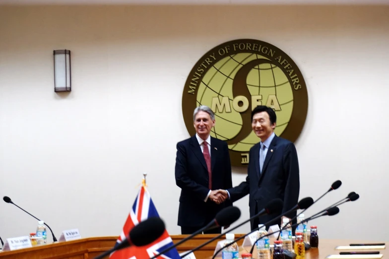 two men are shaking hands at a table