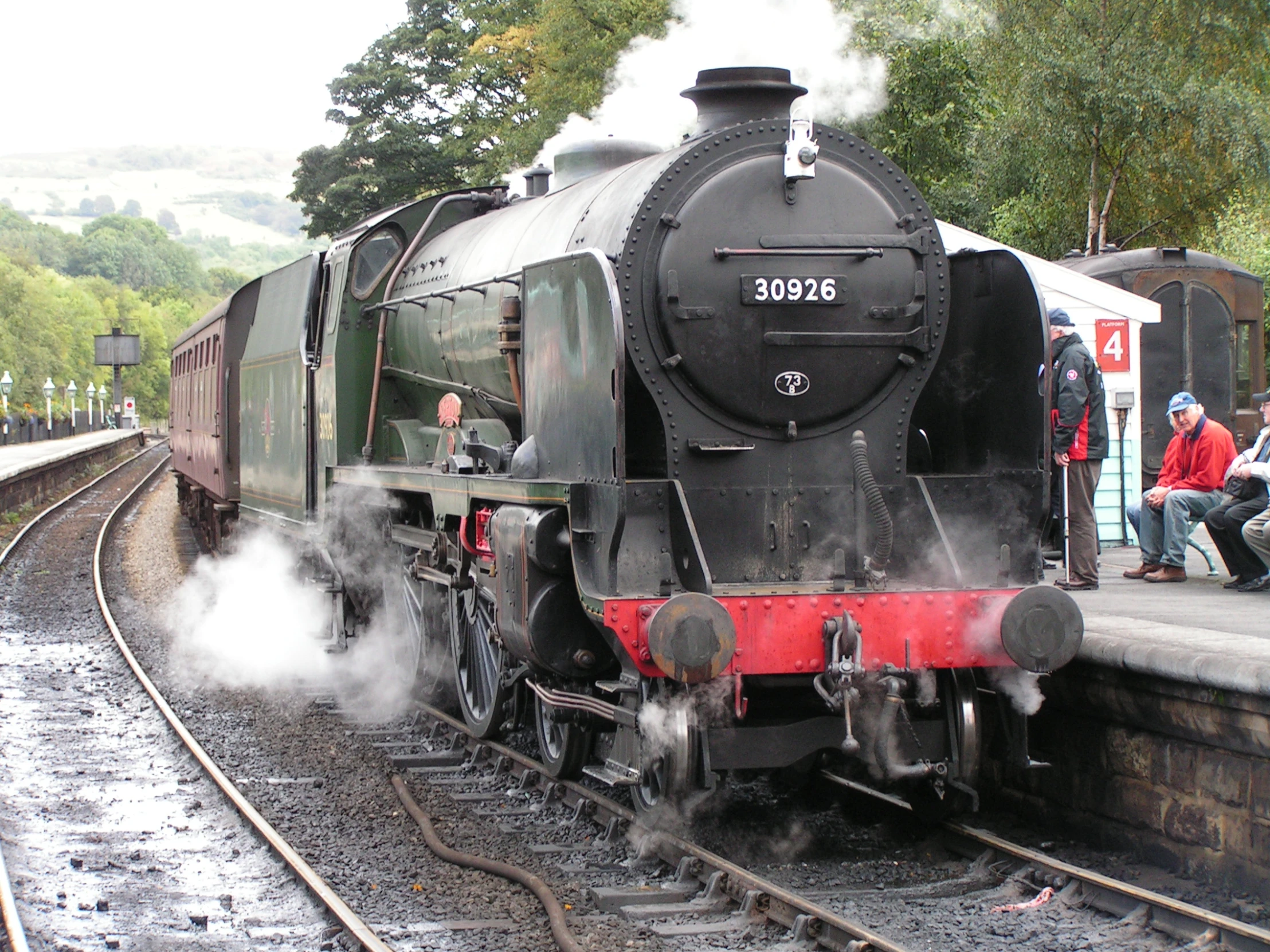 a black train stopped at the platform with steam coming from it