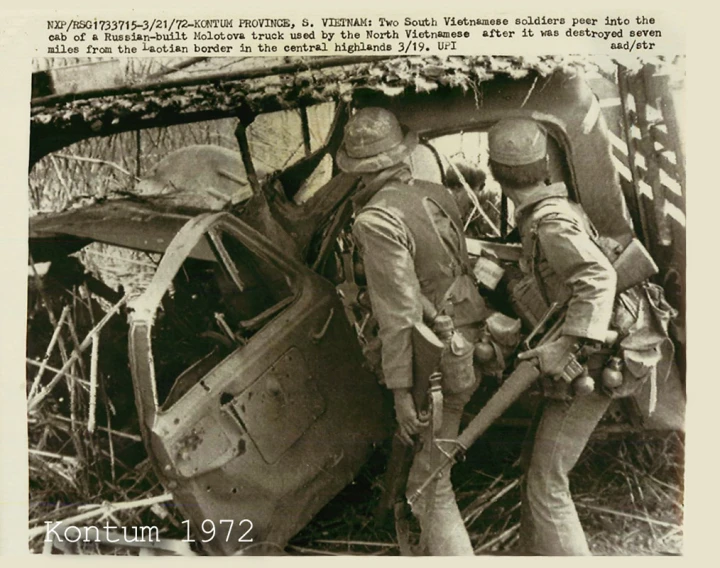 two men standing next to an airplane, in the woods