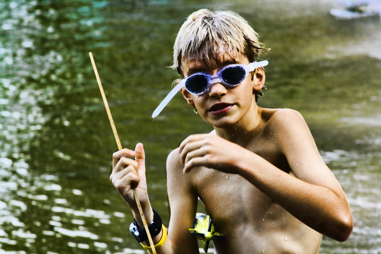 there is a boy with shades on, holding a fishing pole