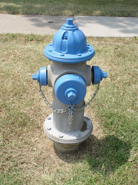 an old fire hydrant sits on the lawn next to a sidewalk