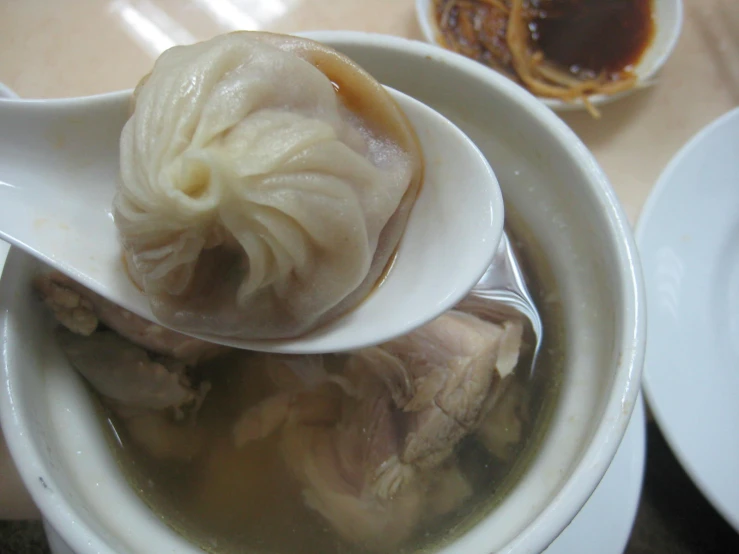 the soup is prepared with dumplings in an asian bowl