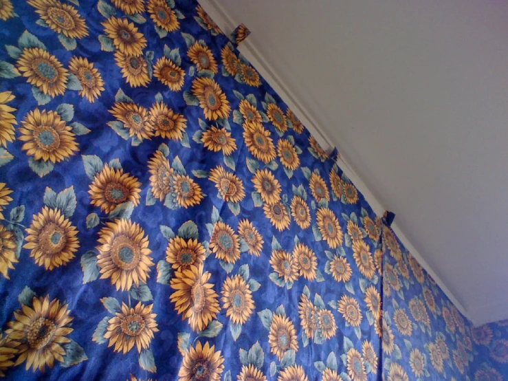 a bed with blue and orange sunflowers is under a ceiling