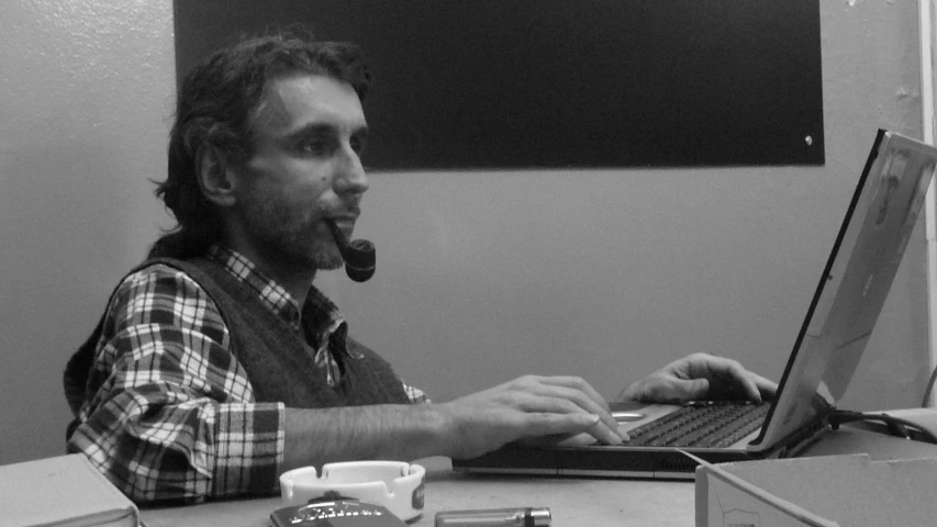 man on his laptop sitting at a desk with a mug in front of him