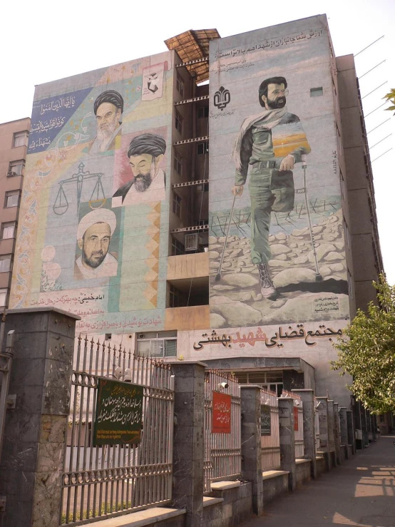 a building that has been painted in arabic and has multiple images on the side of it