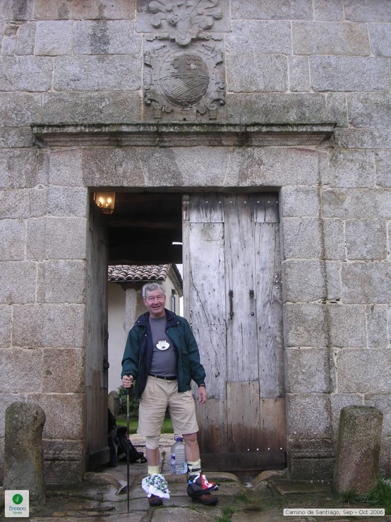 an older gentleman standing in the doorway of a small building