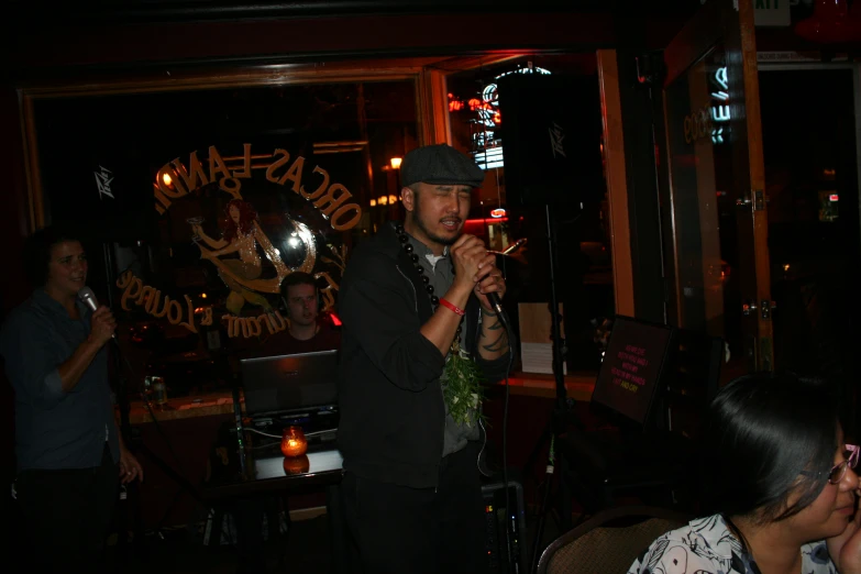 man singing into a microphone at a bar