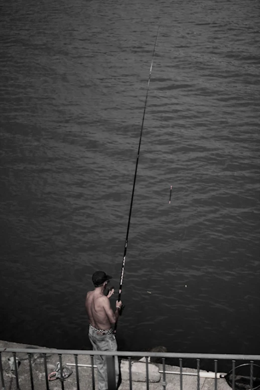 the man is fishing near the water at night