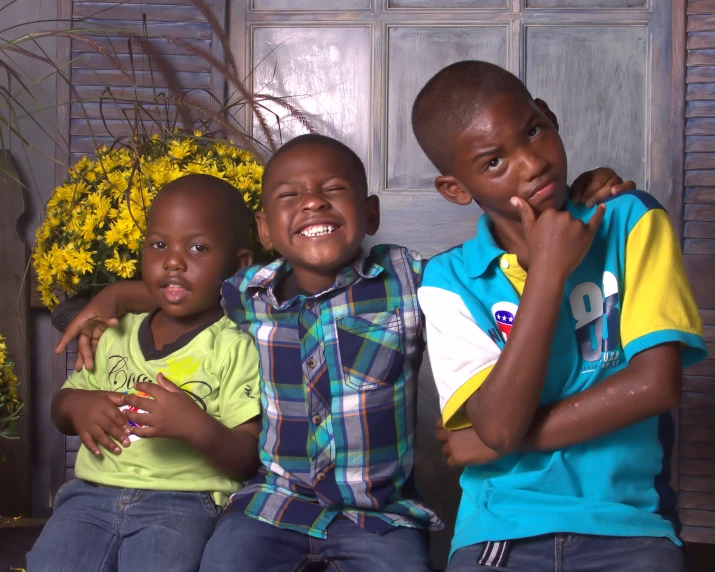 three children posing for a picture with a flower behind them