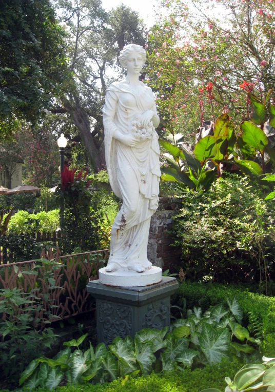 a statue in a garden of greenery that looks like it is part of a statue